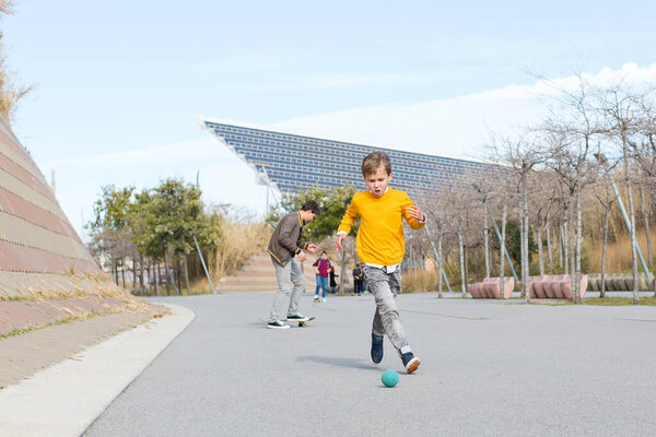 Стильный красивый мальчик, подросток играет с мячом, на улице