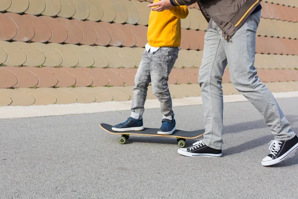 Батько вчить свого сина кататися на скейтборді, на відкритому повітрі — стокове фото
