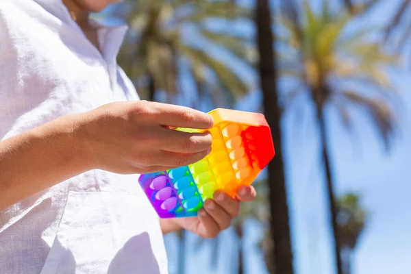 Boy playing with rainbow anti stress pop it toy, outdoors — Stock Photo, Image