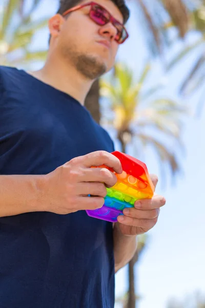 Homem com arco-íris anti estresse pop-lo brinquedo, ao ar livre — Fotografia de Stock