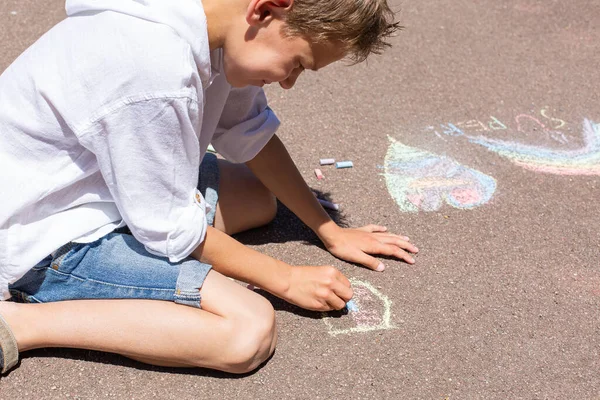 Pojken ritar med krita på trottoaren. — Stockfoto