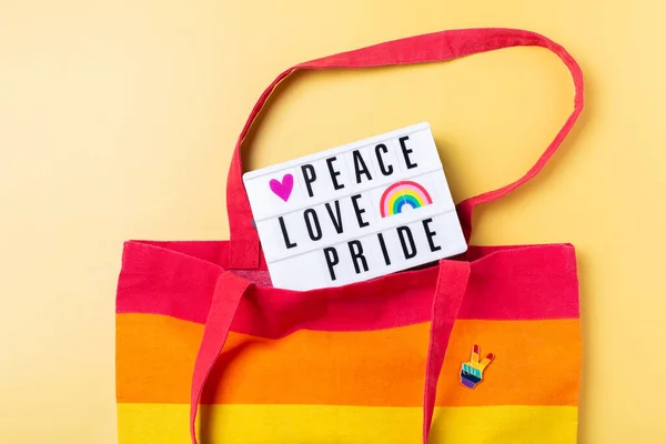 Paz amor orgullo texto, arco iris reutilizable bolsa sobre fondo amarillo —  Fotos de Stock