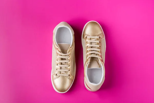 Pair of golden female sneakers on pink background — Stock Photo, Image