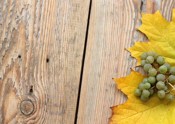 Feuilles et raisins marron sur texture bois — Photo