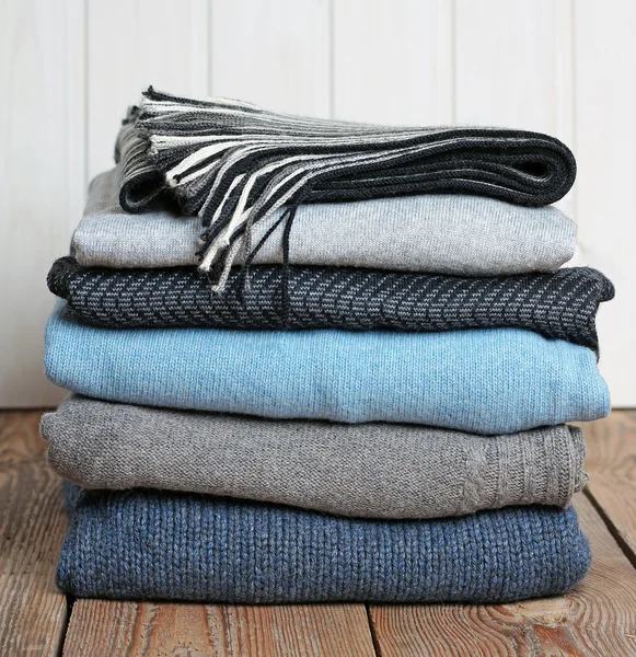 Stack of warm woolen clothing on a wooden table — Stock Photo, Image