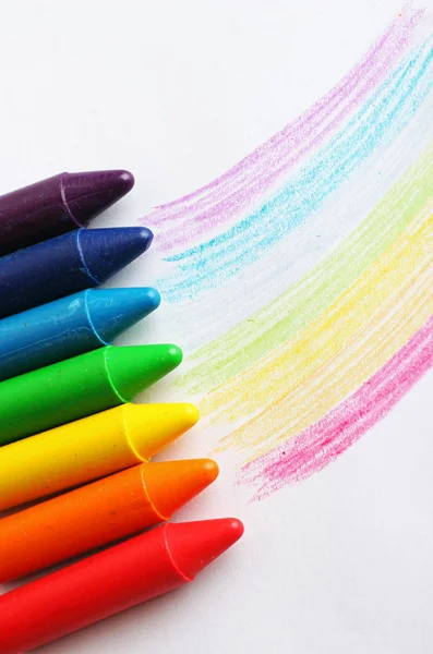 Oil pastel crayons lying on a paper with pictured rainbow — Stock Photo, Image