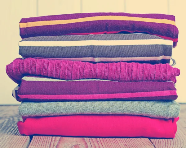 Stack of warm knitting clothing on a wooden table — Stock Photo, Image