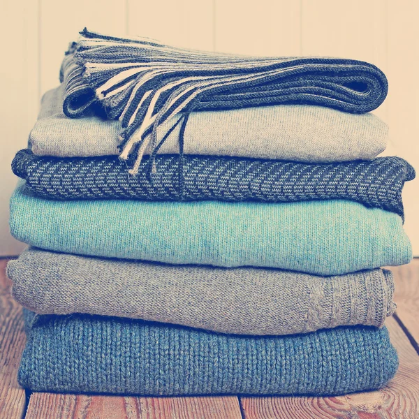 Stack of warm woolen clothing on a wooden table — Stock Photo, Image