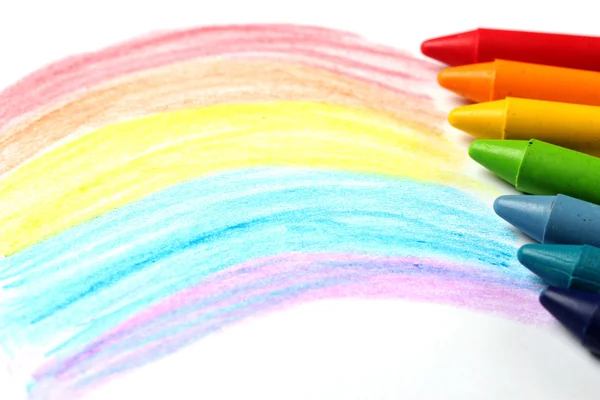 Масляные пастельные карандаши лежат на бумаге с раскрашенной радугой — стоковое фото