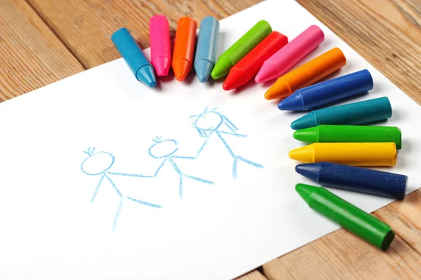 Oil pastel crayons lying on a paper with painted family — Stock Photo, Image