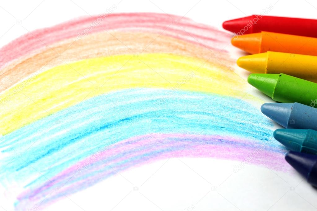 Oil pastel crayons lying on a paper with painted rainbow