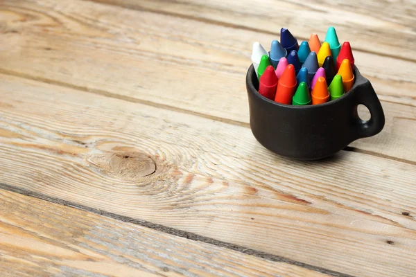 Crayons pastel à l'huile dans une tasse sur une table en bois — Photo