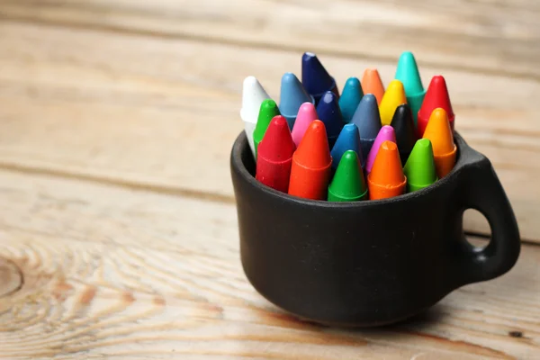 Oil pastel crayons in a mug on a wooden table — Stock Photo, Image