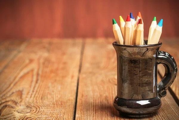 Олівці в чашці на дерев'яному столі — стокове фото