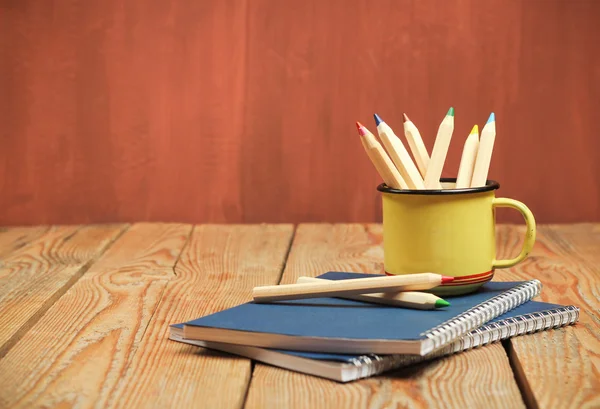 Lápices en una taza sobre una mesa de madera — Foto de Stock