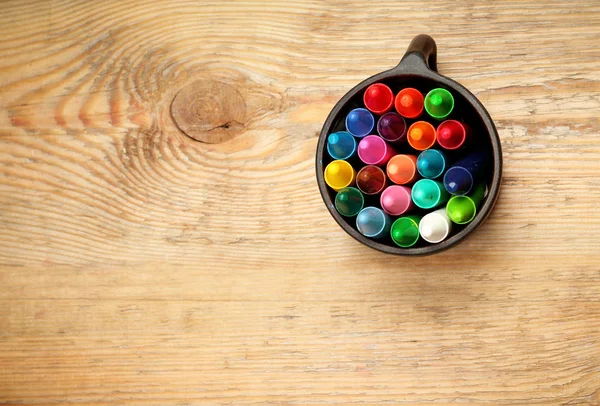 Kleurpotloden in een mok op een houten tafel — Stockfoto