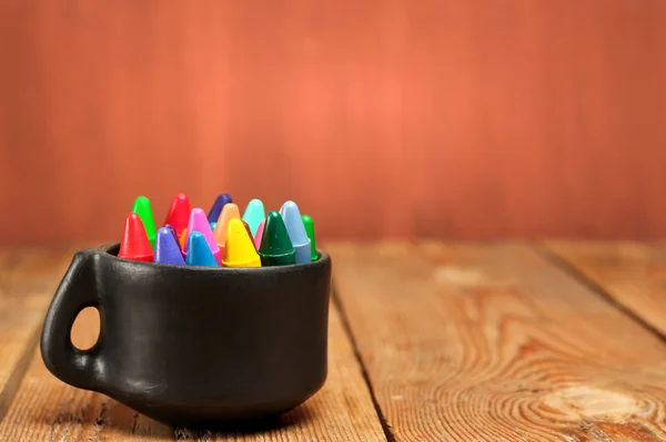 Kleurpotloden in een mok op een houten tafel — Stockfoto