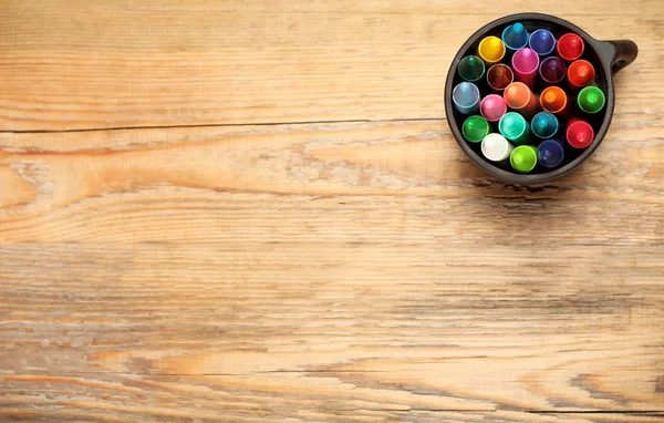 Kleurpotloden in een mok op een houten tafel — Stockfoto