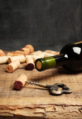 Wine corks, bottle and corkscrew on a wooden table