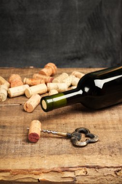 Wine corks, bottle and corkscrew on a wooden table