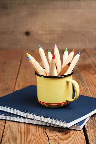 Lápices en una taza sobre una mesa de madera — Foto de Stock