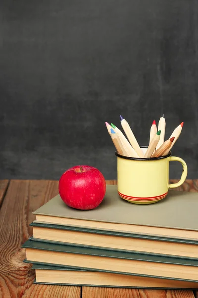 Pencils in a mug, books and apple — Stockfoto
