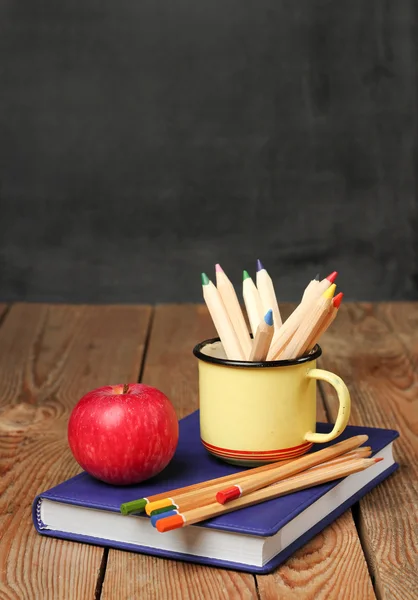 Pencils in a mug, book and apple — Stockfoto