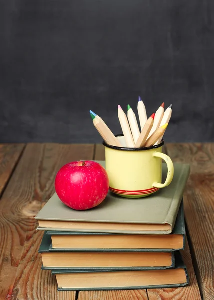 Pencils in a mug, books and apple — Stock Fotó