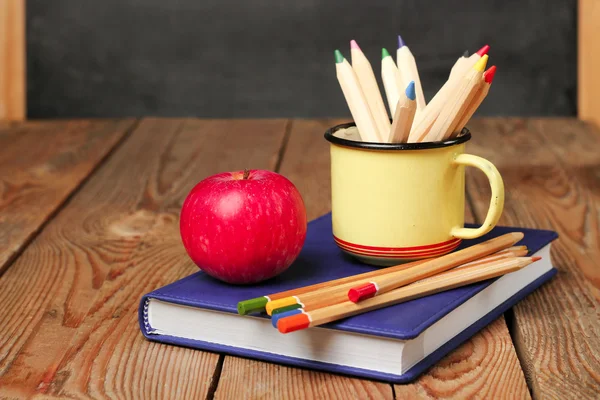 Pencils in a mug, book and apple — Stockfoto