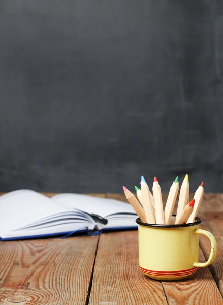 Pencils in a mug, open notebook and chalkboard — Zdjęcie stockowe