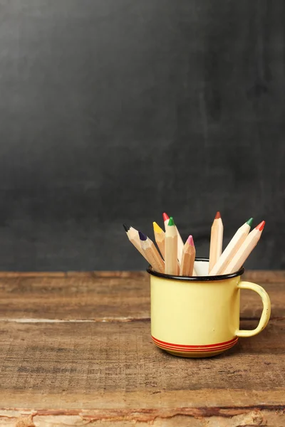 Pencils in a mug on a wooden table and chalkboard — Φωτογραφία Αρχείου