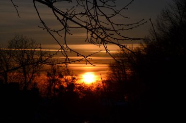 Şehirde gün batımı çok güzeldir. Kızıl gökyüzünün arka planına karşı yuvarlak anten siluetleri.