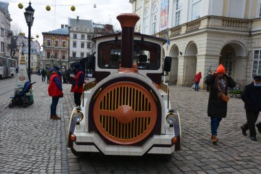 Lviv, Ukrayna. 7 Ocak 2021. Lviv 'in ana meydanında turist tramvayı. Rynok Meydanı 'nda antik binalar, kaldırımlar ve turist kalabalığı. Noel günleri geziler..