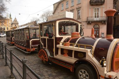 Lviv, Ukrayna. 7 Ocak 2021. Lviv 'in ana meydanında turist tramvayı. Rynok Meydanı 'nda antik binalar, kaldırımlar ve turist kalabalığı. Noel günleri geziler..