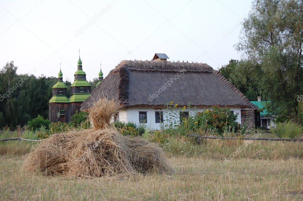 Old Ukrainian house. Ukrainian hut of the nineteenth century. Summer landscape, flowers in front of the house, sunlight. Village Pirogovo.
