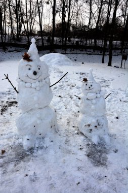 Kar tarlasında şık şapkalı ve eşarplı komik kardan adam. Noel 'den önceki sabah. Komik kardan adamlar. Hediyelerle dolu bir çantayla kardan adam. Kardan adam kırmızı burunlu, kış şapkası ve eşarbıyla duruyor..