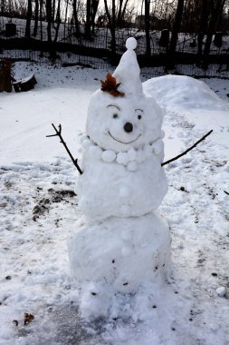 Kar tarlasında şık şapkalı ve eşarplı komik kardan adam. Noel 'den önceki sabah. Komik kardan adamlar. Hediyelerle dolu bir çantayla kardan adam. Kardan adam kırmızı burunlu, kış şapkası ve eşarbıyla duruyor..
