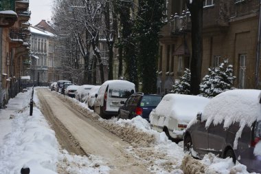 Kar, kış günü kar yağışından sonra arabaları kapladı. Otoparktaki kar fırtınasında araçlar karla kaplandı. Karla kaplı yollar ve şehrin sokakları.