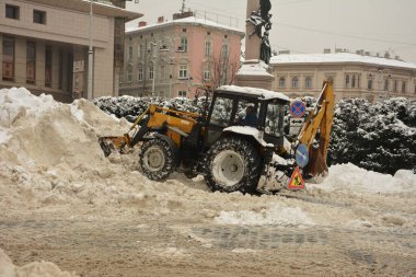 Lviv. Ukrayna. Şubat 2021 'de kar temizleme traktörü döner fırçayla karları parktaki toprak zeminden süpürüyor. Çekici kepçeli ve otomatik fırçalı kar kaldırır. Belediye Kamu Hizmeti