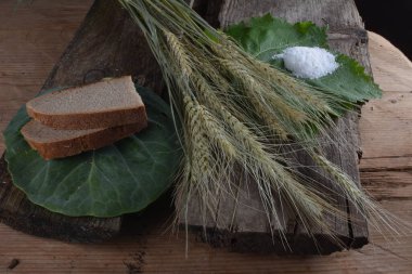 Ekmek ve tuz eski bir rustik ahşap arka planda. Ekmek ve tuz, masada buğday kulakları.