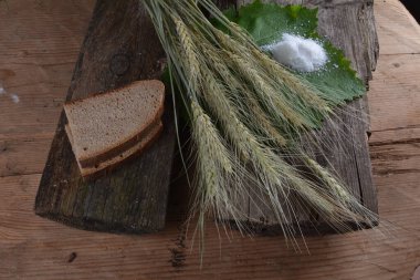 Ekmek ve tuz eski bir rustik ahşap arka planda. Ekmek ve tuz, masada buğday kulakları.