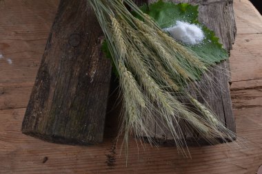 Ekmek ve tuz eski bir rustik ahşap arka planda. Ekmek ve tuz, masada buğday kulakları.