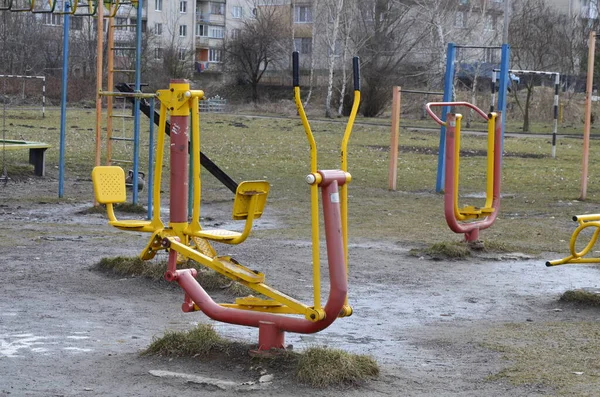 Sports simulators on the playground: horizontal bars and other equipment.One colored metal sports simulator on the street in the green grass on the lake.Sports ground.