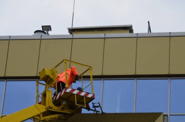 Rivne. Ukrayna. Nisan 2021 Bir otomotiv hidrolik alıcısı kullanarak yüksek binaların camlarını yıka. Yükseklikte çalış.