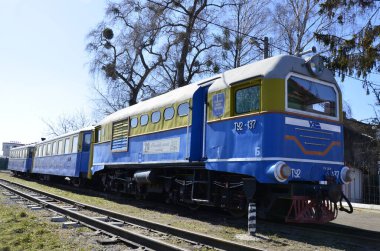 Rivne . Ukrayna. Nisan, 2021 Dar ölçülü çocuk demiryolu lokomotifinin arka planında demiryolu trafik ışıkları.