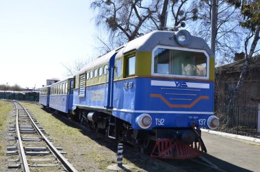 Rivne . Ukrayna. Nisan, 2021 Dar ölçülü çocuk demiryolu lokomotifinin arka planında demiryolu trafik ışıkları.