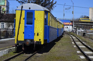 Rivne . Ukrayna. Nisan, 2021 Dar ölçülü çocuk demiryolu lokomotifinin arka planında demiryolu trafik ışıkları.