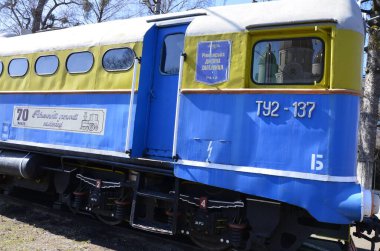 Rivne . Ukrayna. Nisan, 2021 Dar ölçülü çocuk demiryolu lokomotifinin arka planında demiryolu trafik ışıkları.