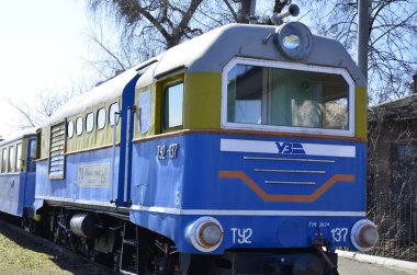 Rivne . Ukrayna. Nisan, 2021 Dar ölçülü çocuk demiryolu lokomotifinin arka planında demiryolu trafik ışıkları.