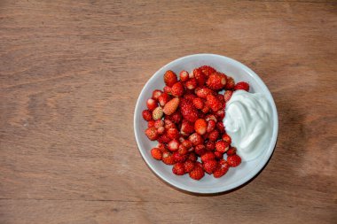 Bir buket yabani çilek. Çilek buketi Ormandaki Eski bir kütük üzerinde. Yabani çilek ve çiçeklerle çevrili.